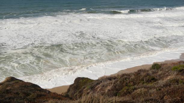 ondas oceânicas e rochas, monterey, norte da califórnia, eua. 17 milhas de carro perto de big sur, resort turístico de golfe à beira-mar na pacific coast highway. espirrando água e brisa do mar da praia de pebble. viagem - route 1 pacific ocean beach cliff - fotografias e filmes do acervo