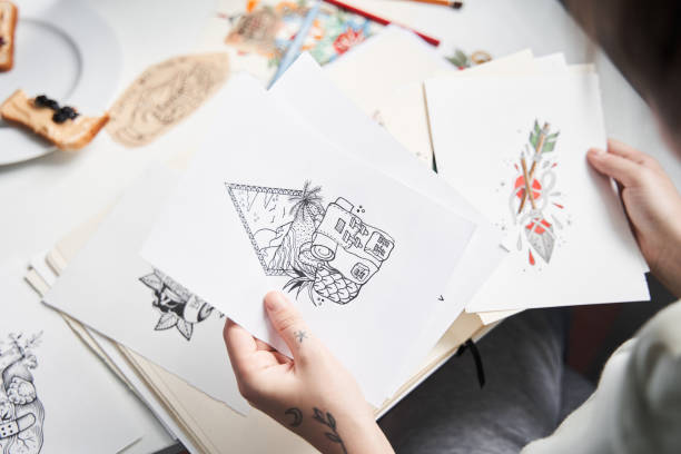 istock Woman holding two different sketches and looking on it while making choice 1309948925