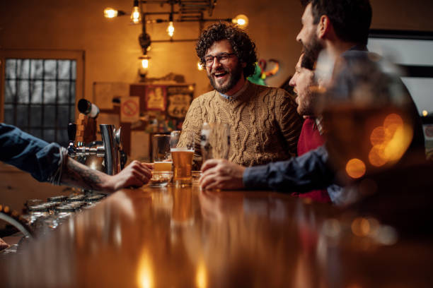 gruppo di uomini felici che bevono birra al bar - bancone bar foto e immagini stock
