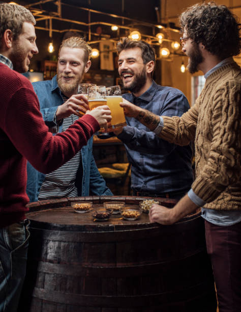 group of happy men drinking beer at the pub, making a toast - irish culture beer drinking pub imagens e fotografias de stock