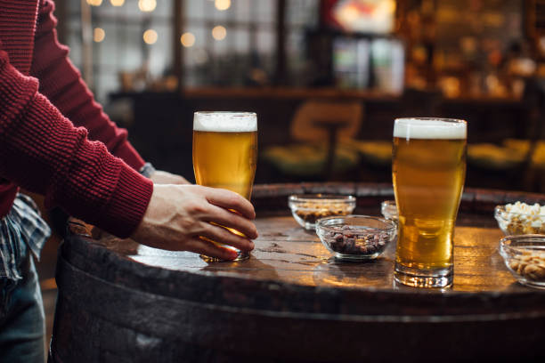 Anonymous Man Standing in a Pub Holding a Glass of Cold Beer