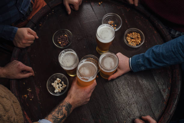 hands of people toasting with beer at a pub - bird's eye view - beer nuts imagens e fotografias de stock