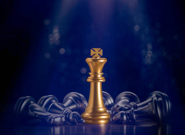 istock Golden king chess stand which flare light surrounded by falling around silver chess pieces to fighting with teamwork to victory, business strategy concept and leader and teamwork concept for success. 1309949516