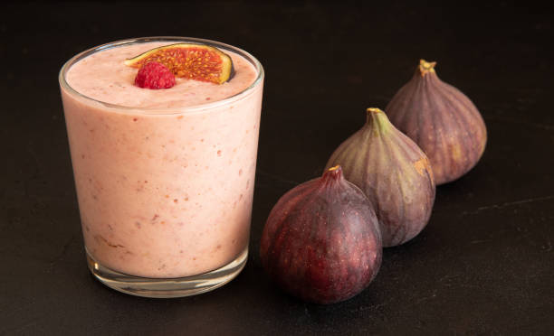 A glass cup of yogurt, with raspberries on top. Next to three pieces of figs. Selective focus. stock photo