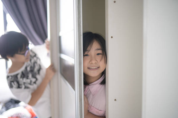 istock 2 Asian Chinese sibling playing in the wardrobe while father is installing cabinet 1309957534
