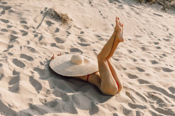istock Attractive woman in bikini with big straw hat at sandy beach. 1309959097