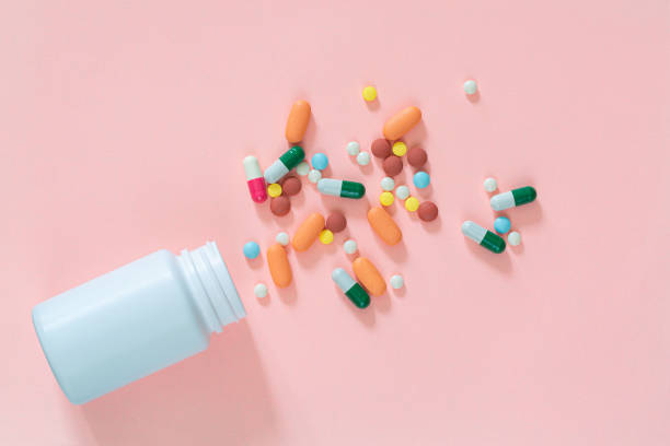 istock Multicolored tablets, pills, capsules in plastic bottle on pink background, copy space. Medicine, vitamin and nutritional supplements concept. 1309960509