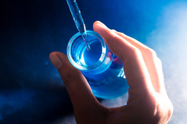 istock Flask in scientist hand with lab glassware background in laboratory. Science or chemical research and development concept. 1309960511