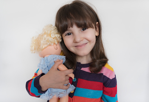 one plastic doll in a colored dress and brown hair stands on a gray table against a green wall