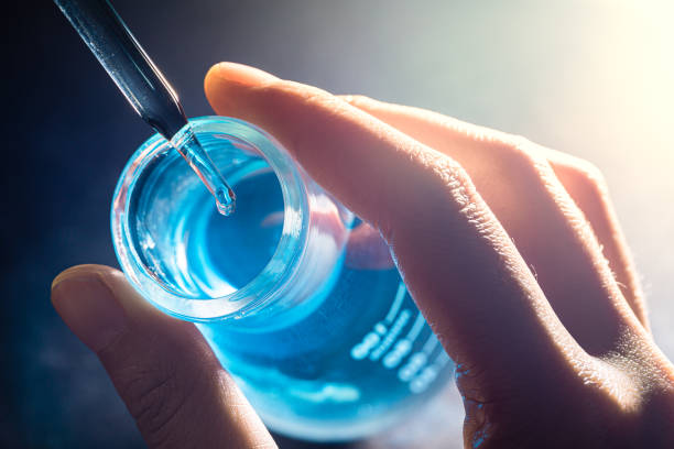 istock Flask in scientist hand with lab glassware background in laboratory. Science or chemical research and development concept. 1309960541