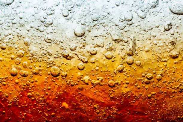 nahaufnahme der eiswürfel im dunklen cola-hintergrund. textur des kühlenden süßen sommergetränks mit schaum und makroblasen an der glaswand. fizzing oder schweben bis zur oberfläche.. - non alcoholic beverage fotos stock-fotos und bilder