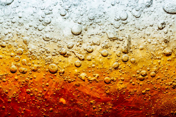 fermez-vous vers le haut de la vue des glaçons dans le fond foncé de cola. texture de la boisson douce rafraîchissante d’été avec la mousse et les bulles de macro sur le mur en verre. grésillement ou flottant jusqu’au sommet de la surface.. - whisky alcohol glass image photos et images de collection