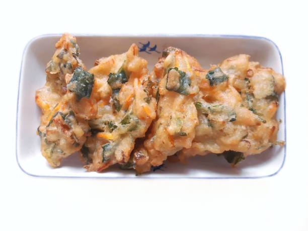 Bakwan or a vegetable fritter or gorengan from Indonesian cuisine. Bakwan on a white plate. The bakwan's ingredients are vegetables; usually beansprouts, shredded cabbages and carrots, battered and deep fried in cooking oil gorengan stock pictures, royalty-free photos & images