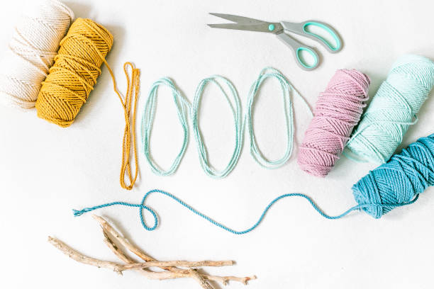 A arrangement of colourful cotton cords with scissors and driftwood