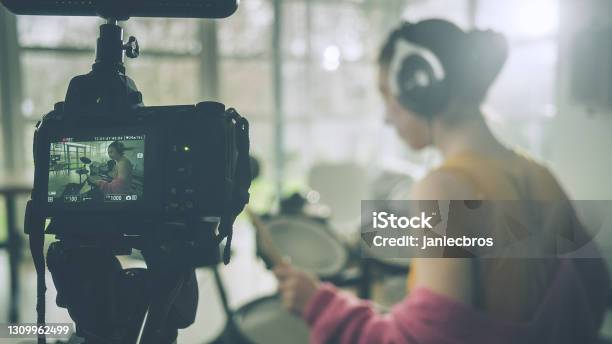 Young Woman Practicing On Electronic Drums In Her Living Room Recording Music Session Stock Photo - Download Image Now