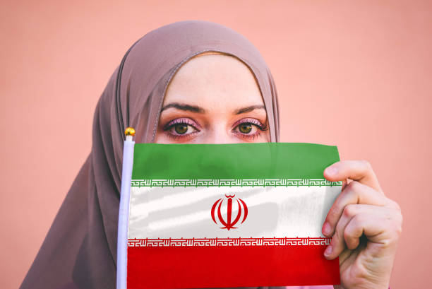 ヒジャーブのイスラム教徒の女性は、イランの旗を保持しています - iran ストックフォトと画像