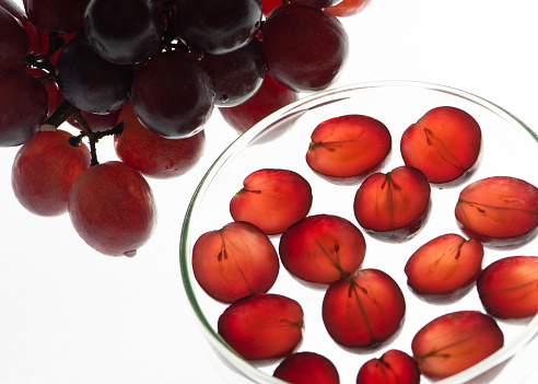 Red grapes and Petri dish with slice of red grape. Ingredient for organic bio cosmetic. Flat lay, top view.