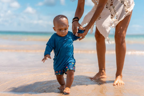menino dando seus primeiros passos na praia - grandmother grandson baby mother - fotografias e filmes do acervo
