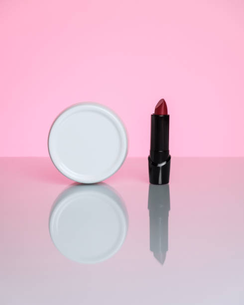 istock Hand cream and red lipstick on a pink background with reflection. 1309970300