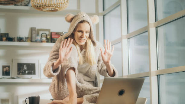 missing a friend during lockdown. woman doing video call in cute bear onesie - onesie imagens e fotografias de stock