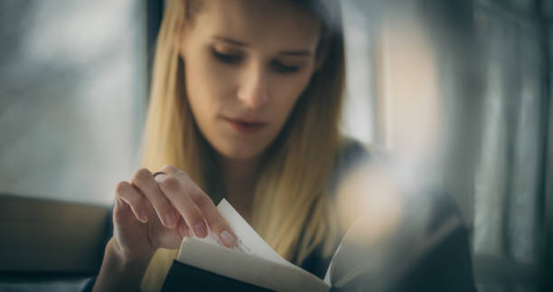 istock Woman sitting on the windowsill and enthusiastically reading a book 1309971277