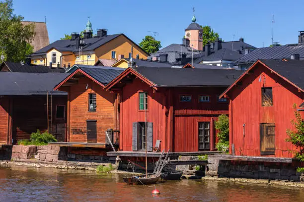 Old boat and red wooden buildings on the river in Porvoo, Finland