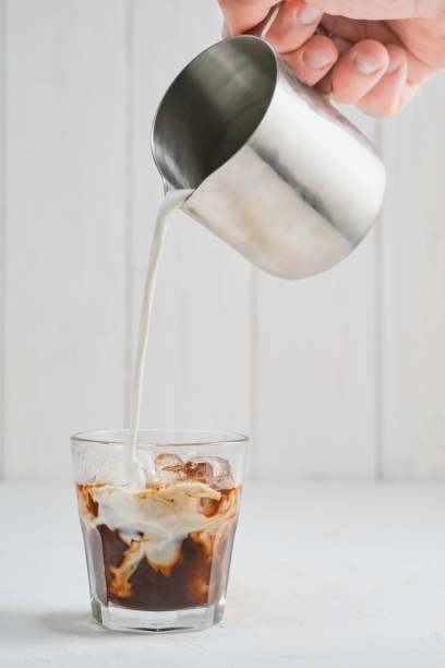 istock Iced coffee on a gray concrete table, pouring the cream, showcasing the texture and refreshing look of the drink. Close-up on cold coffee, selective focus, vertical frame 1309975864
