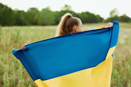 Niña ucraniana con camisa bordada vyshyvanka con bandera amarilla y azul de Ucrania en el campo. photo