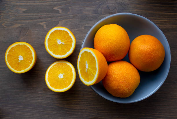 istock Fresh oranges in a light blue bowl on a dark wood background 1309978293