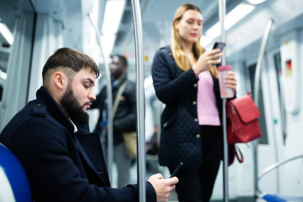 istock Guy with phone sitting in subway car 1309978321