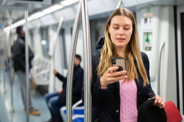 istock Young woman browsing on phone in metro car 1309978338