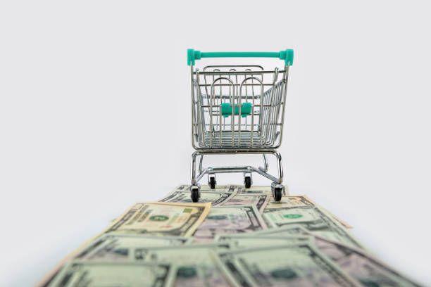 istock shopping cart on US dollars banknotes road isolated on white background, selective focus 1309978375