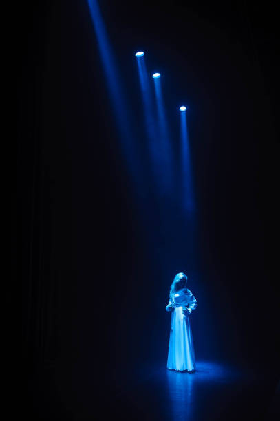 istock Actress, singer on stage in the rays of blue light. 1309979049