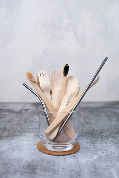 istock Basic set eco friendly reusable bamboo cutlery, toothbrushes, metal tubes in a transparent glass beaker on gray background. Concept of environmental protection, plastic free, zero waste. 1309979386