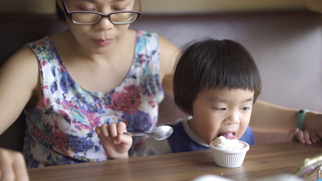 Happy Asian baby boy eating ice cream with Mother at the restaurant