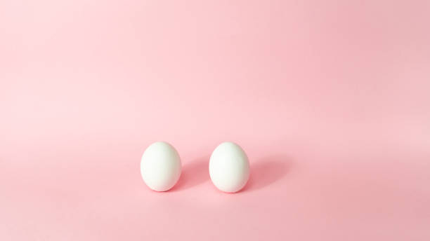 istock Two white chicken eggs isolated on light pink pastel background. Happy Easter Day. Greeting card. 1309983348