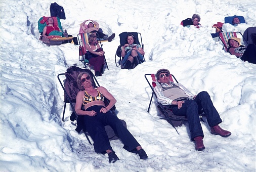 Bavaria, Germany, 1978. Winter sport tourists basking in lounge chairs in the snow.