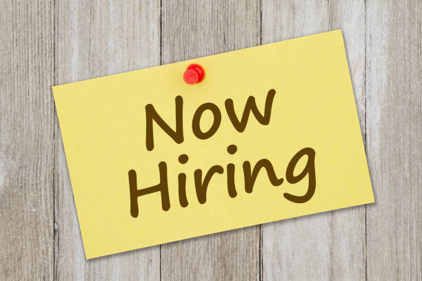 istock Now hiring message on retro yellow paper index card with pushpin 1309985433