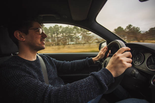 istock Happy guy sitting driving a car with two hands on the steering wheel 1309986121