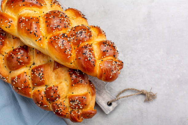 istock Homemade braided bread decorated with sesame seeds. Top view. Light grey background. Copy space. 1309986312