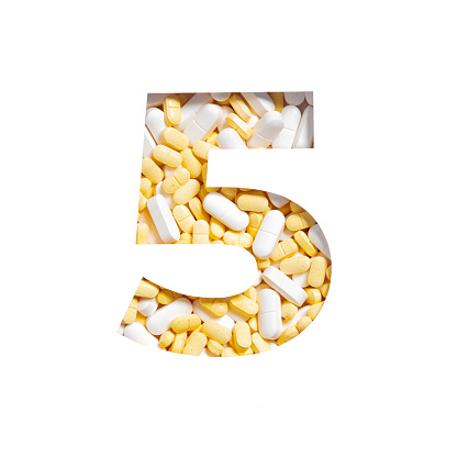 Number five made of pills and paper cut in shape of fifth numeral isolated on white. Pharmacy typeface. High quality photo