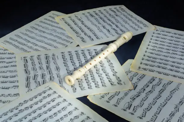 white fipple soprano flute recorder lies on sheet music scores