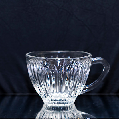 Glass transparent cup for tea or coffee. Glass mug on a black background.