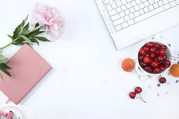 современный женский рабочий стол, домашний офис, чашка с вишней и пионами на светлом столе. здоровый завтрак с ингредиентами, концепция здо� - flower cherry cup tea стоковые фото и изображения