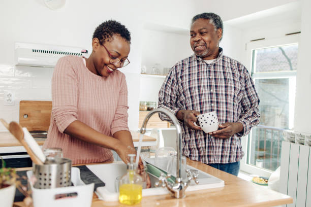 african american senior woman washing dishes and enjoying with her husband - senior getting groomed studio imagens e fotografias de stock