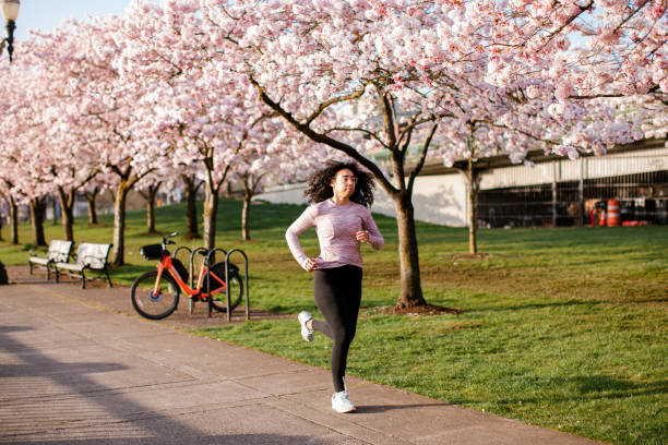 istock Woman Jogging In Spring Tree Blooming City Waterfront 1309991020