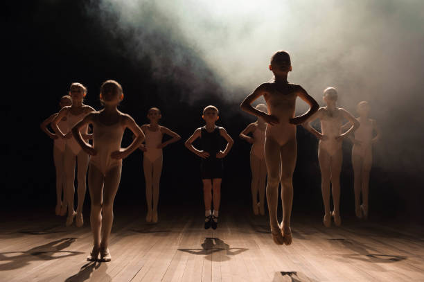 istock Happy children doing ballet jump on a dark lighted scene. 1309991023
