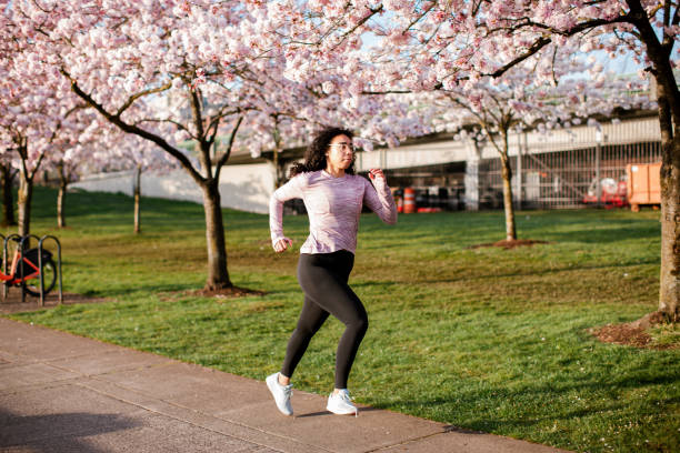 istock Woman Jogging In Spring Tree Blooming City Waterfront 1309991127