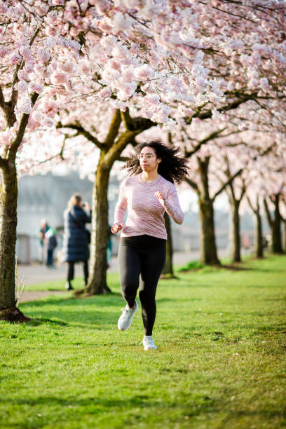 istock Woman Jogging In Spring Tree Blooming City Waterfront 1309991144