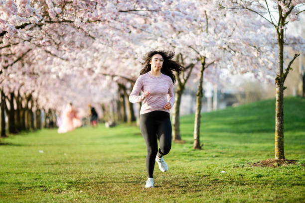 istock Woman Jogging In Spring Tree Blooming City Waterfront 1309991148